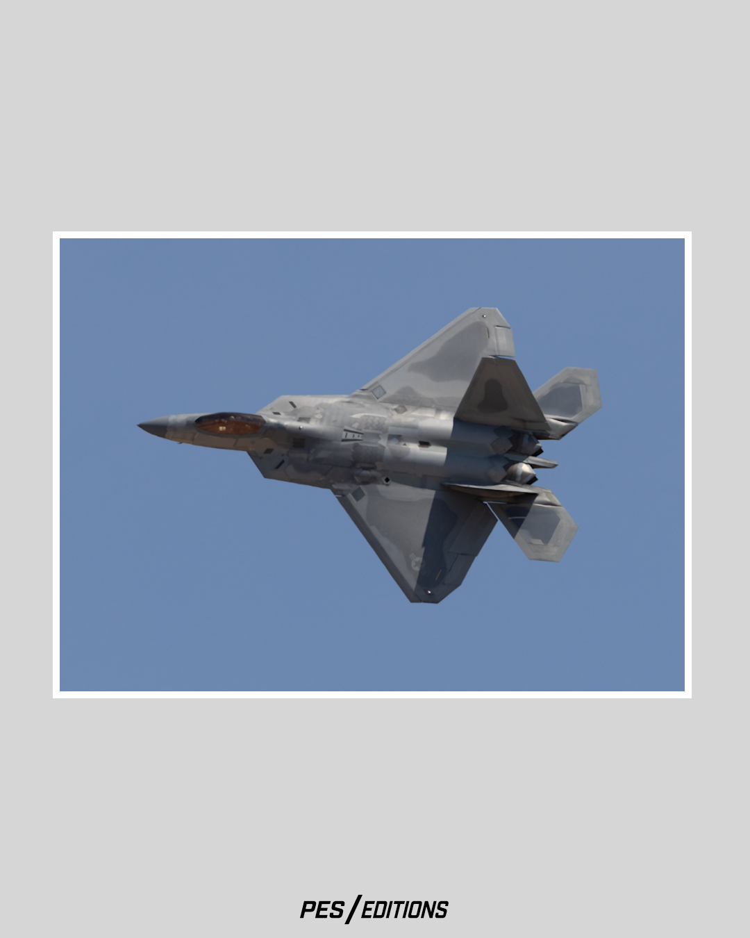 An F-22 Raptor banking aggressively, revealing its complex stealth coating patterns and control surfaces against a clear blue sky.