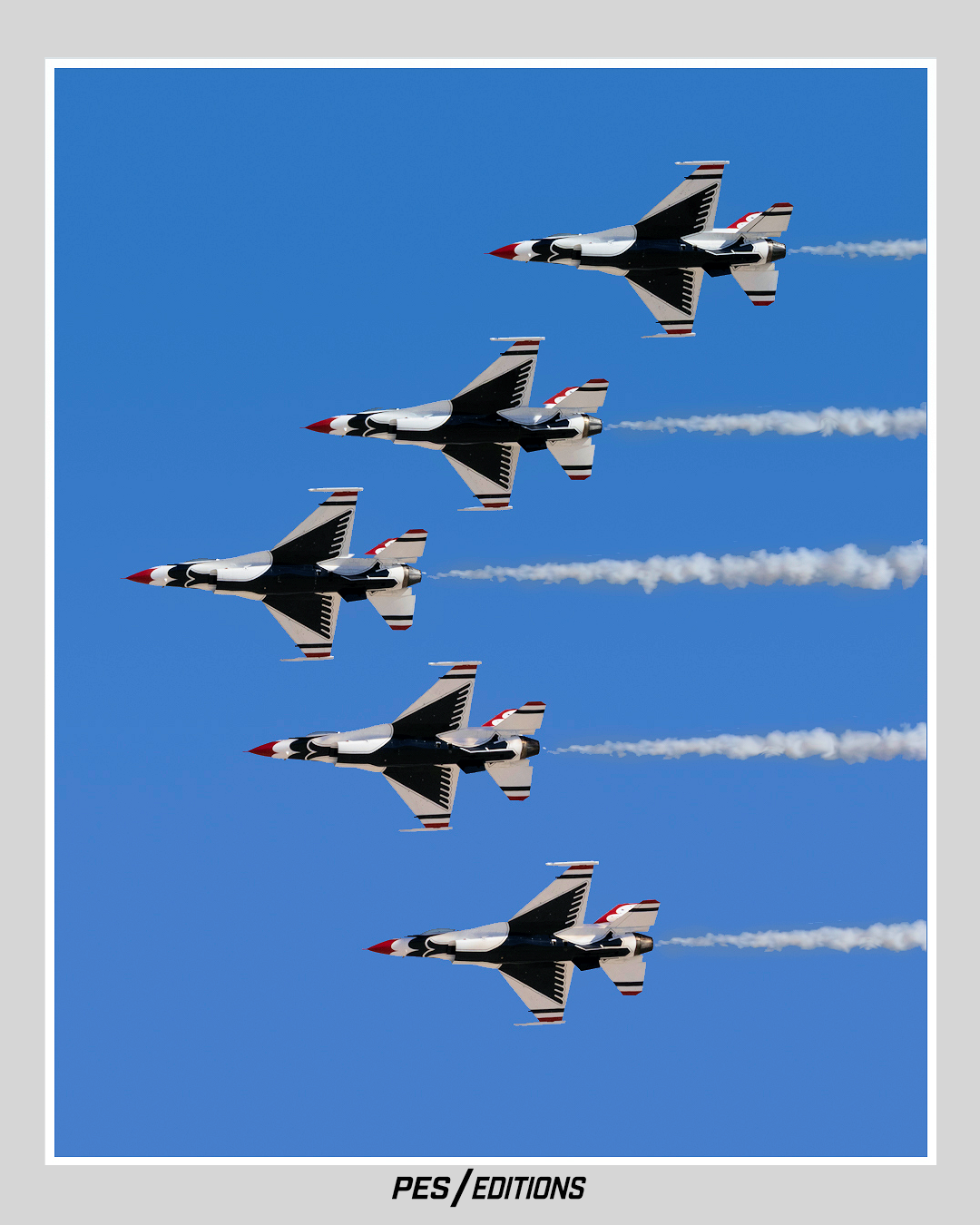 Five United States Air Force Thunderbirds F-16 Fighting Falcon jets are captured mid-flight, performing a synchronized aerial demonstration against a clear blue sky.